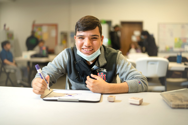 special ed student smiling at the camera during a drawing project