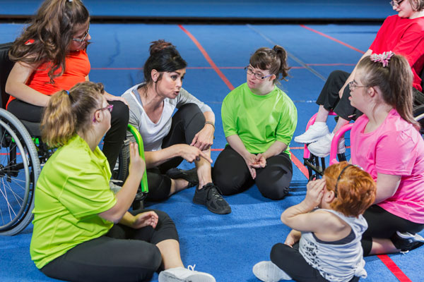 woman talking with special education students on a gymnastics floor