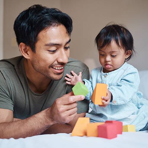 a man playing with a disabled infant with blocks
