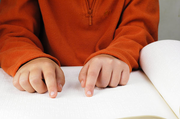 A child's hands reading braille.